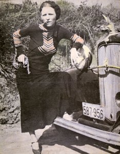 Bonnie Parker pózující „tvrdá“ se zbraní a doutníkem, kolem roku 1934 (černobílá fotografie)